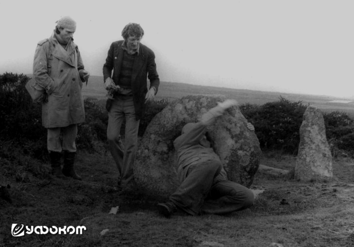Британский фортеанец и эзотерик Джон Мичелл (в центре) наблюдает за математиком Бобом Форрестом, пролезающим через отверстие в якобы целительном камне мегалитического комплекса Мен-ан-Тол во время экспедиции 1977 года. Фото с личного сайта Боба Форреста.