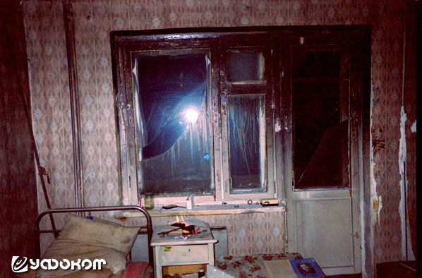 Ф7А – снимок сделан в комнате квартиры №123 в ночное время с фотовспышкой. На тумбочке видно пламя горящего листа бумаги. Видно, что комната существенно пострадала от пожара 1998 года.