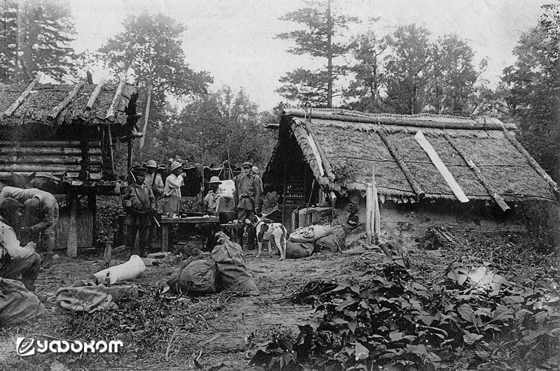 Отряд В. К. Арсеньева (в центре, пьёт из кружки) у китайской фанзы на р. Синанца. Экспедиция 1907 года. Фото из первого тома собрания сочинений в шести томах (Владивосток: Альманах «Рубеж», 2007).